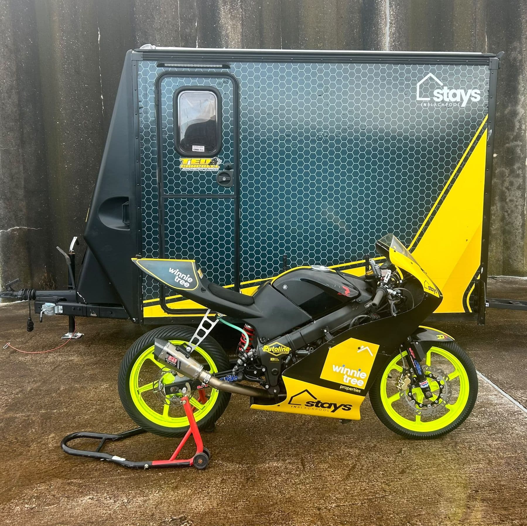 The race bike in front of the Stays-branded team trailer